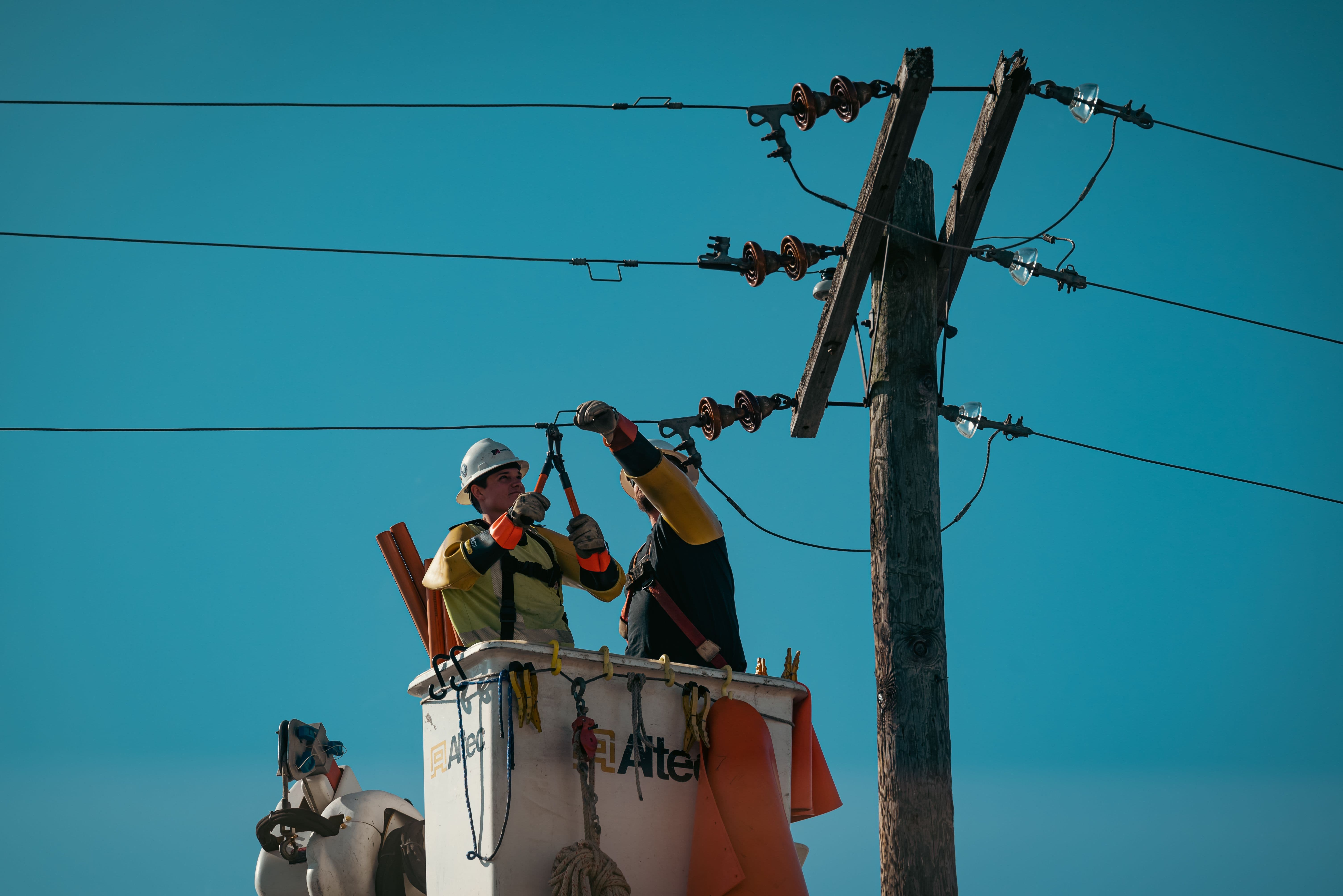 Cuadrilla instalando líneas eléctricas en poste